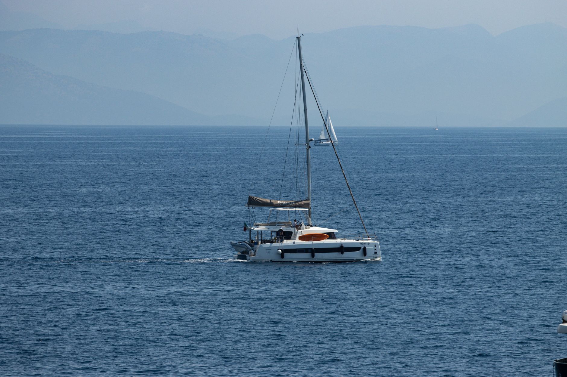 A serene sailing yacht on the calm blue waters of the Ionian Sea, Corfu, Greece.