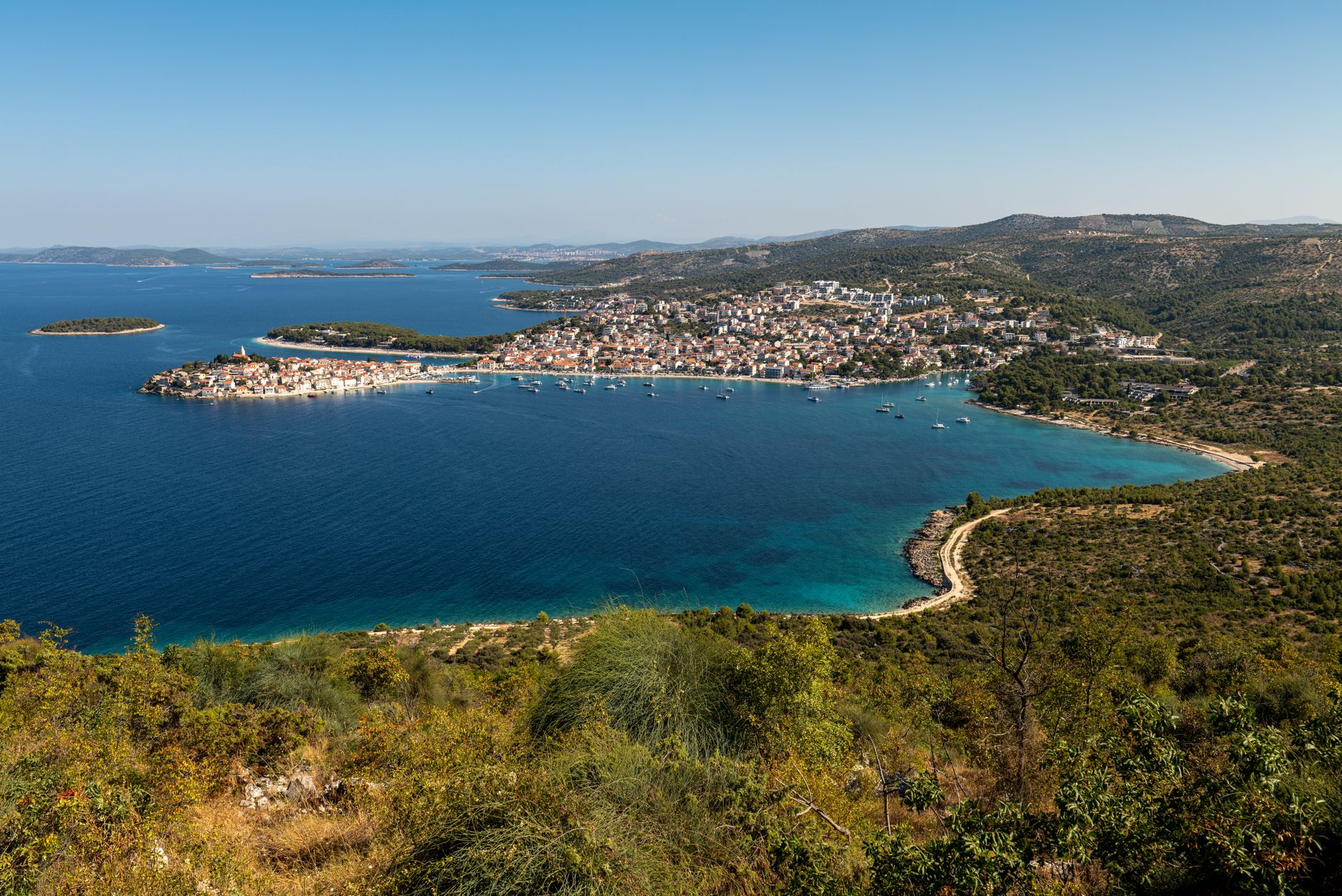 Breathtaking aerial view of Primošten's coastline in Croatia with its vibrant blue waters.