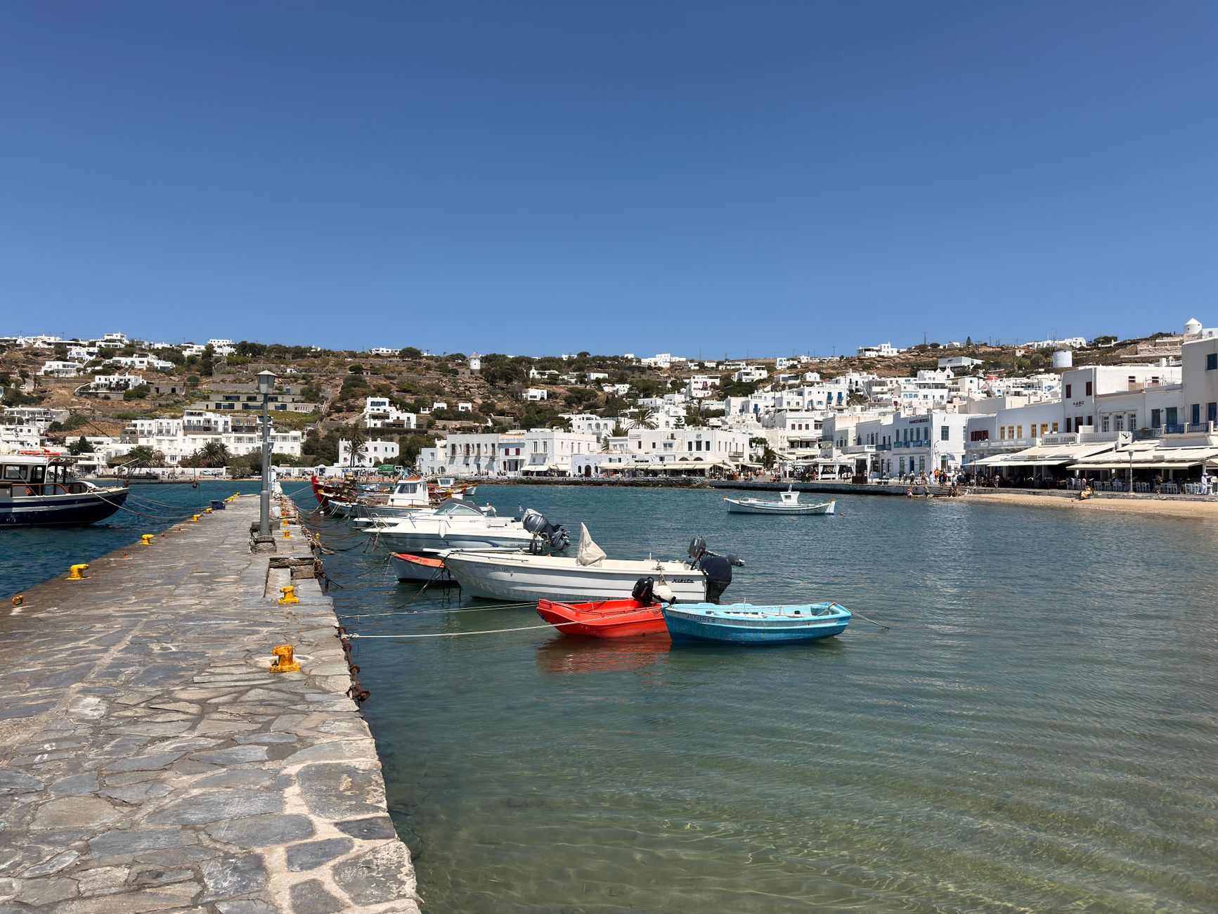 Scenic view of boats docked in a harbor with traditional Greek architecture in the background.