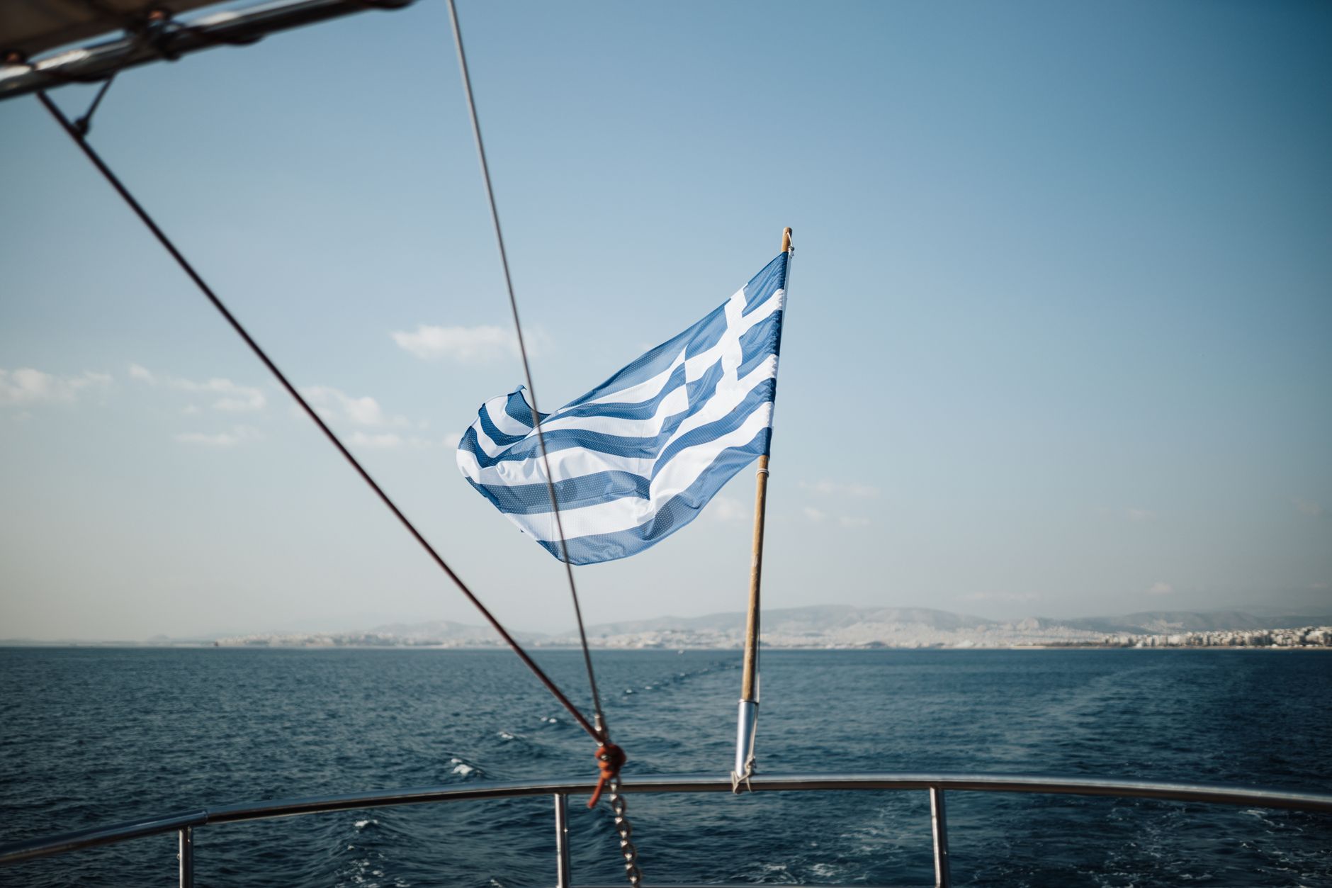 Greek flag on a boat in the Aegean Sea, captured under a clear sky.