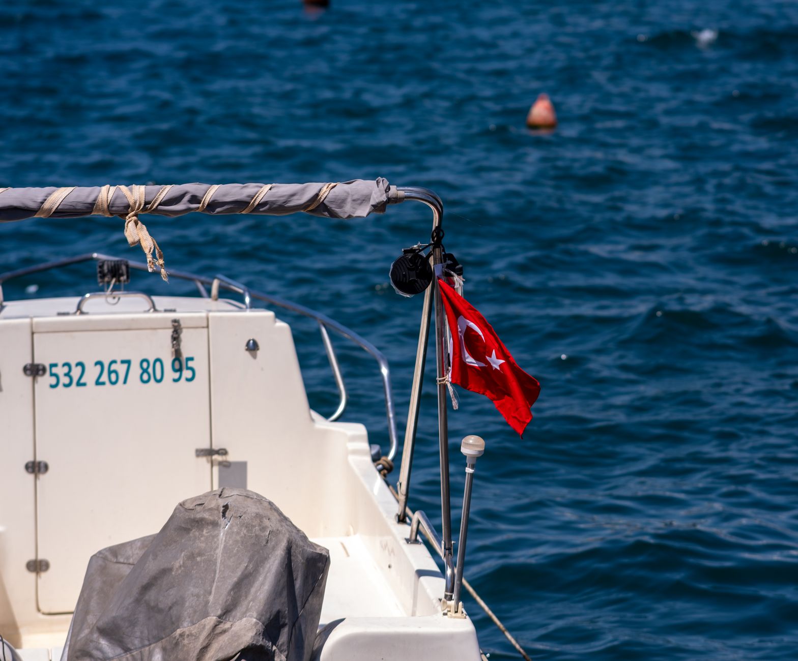 Boat displaying Turkish flag on the clear blue waters of the Aegean Sea in Foça, İzmir.